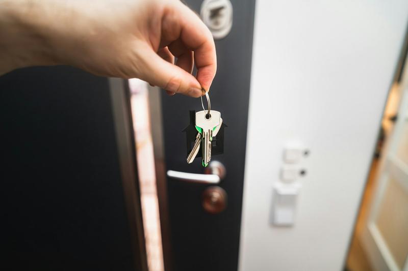 Mano con un juego de llaves delante de una puerta de piso abierta